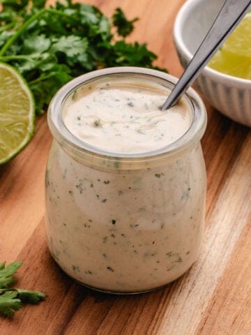 Tahini lime dressing in a jar with a spoon.