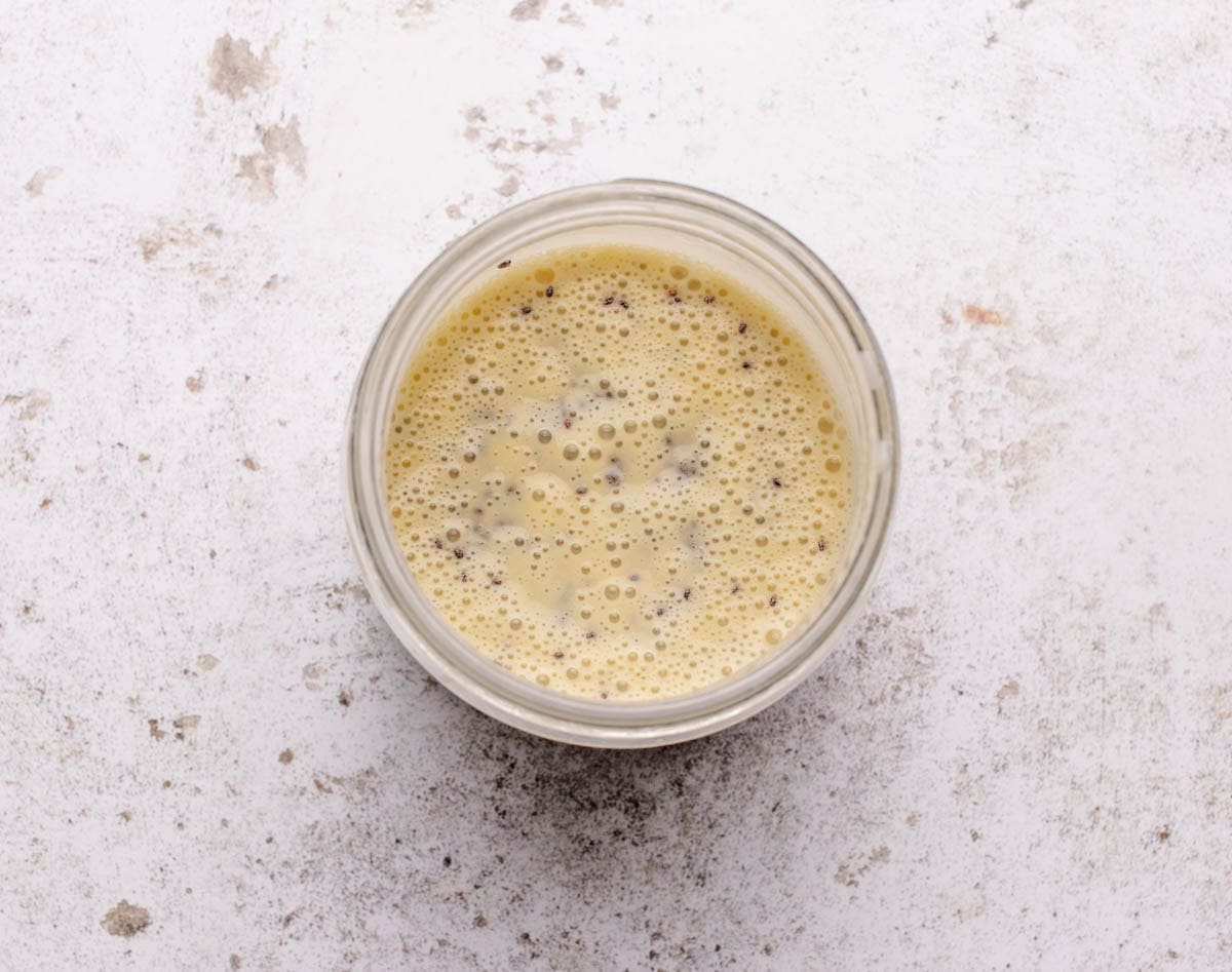 Blended mango, yogurt, and dairy-free milk with chia seeds.