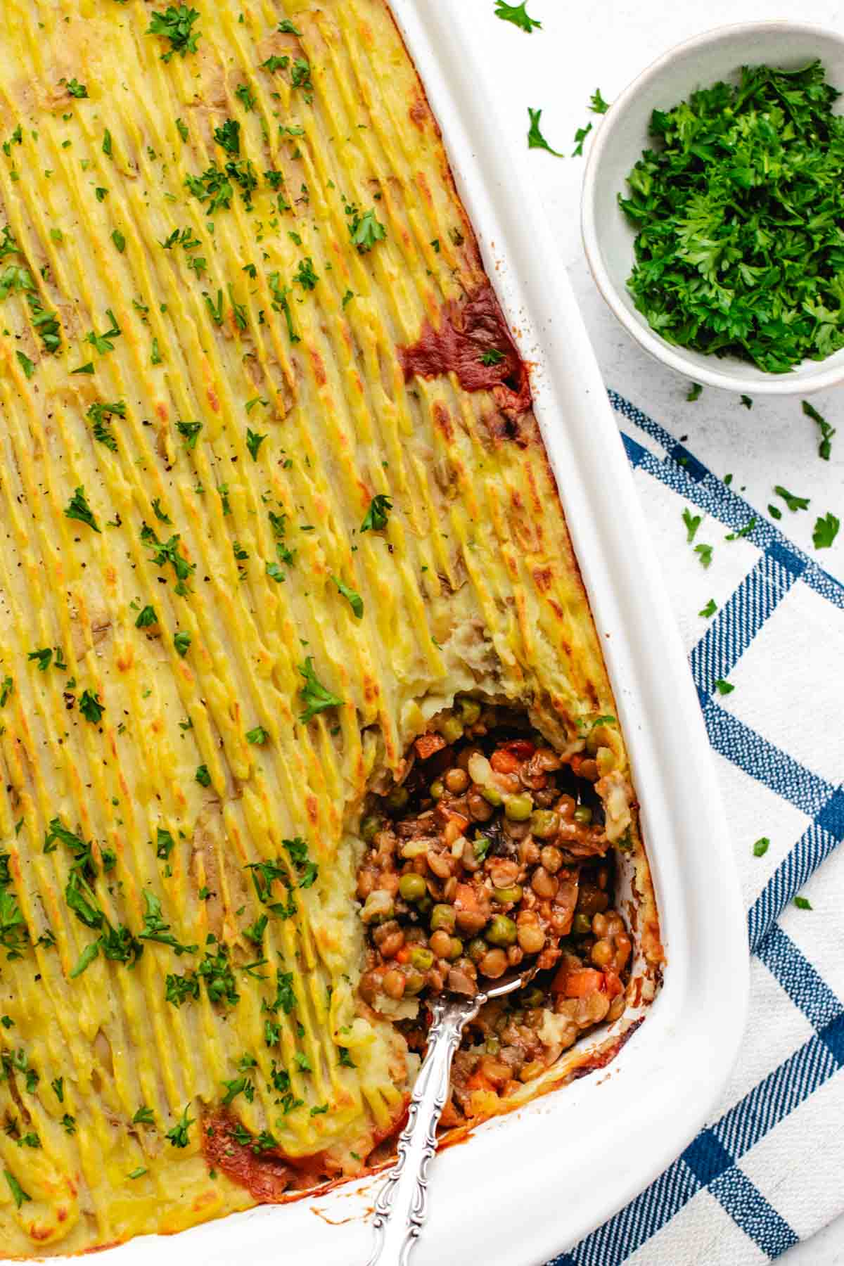 Vegan shepherd's pie in a baking dish with a spoon.