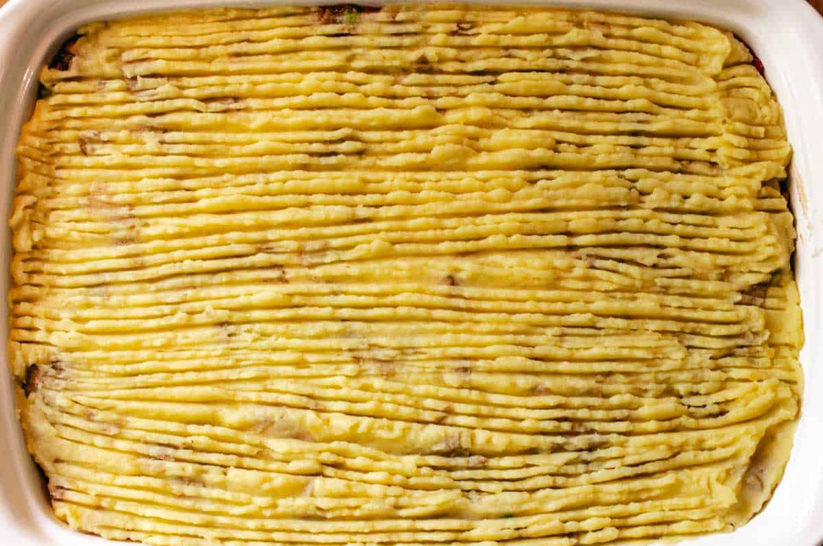 Lentil mushroom pie in a baking dish with ridges from a fork in the mashed potatoes.