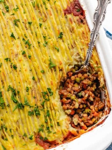 Vegan shepherd's pie in a baking dish with a spoon.