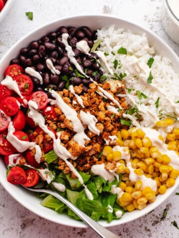 Tofu burrito bowl with black beans, corn, cherry tomatoes, romaine lettuce, and cashew lime crema.