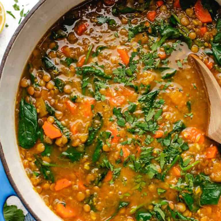 Carrot butternut squash soup in a pot with a wooden spoon.