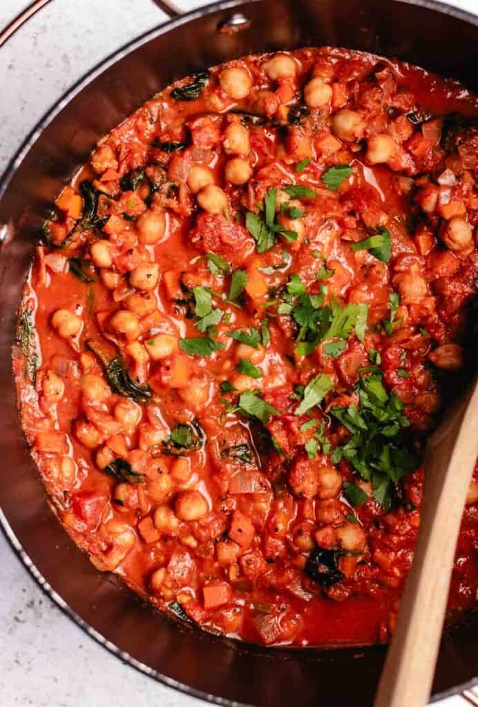 Chickpea tomato stew in a large pot with chopped cilantro on top.
