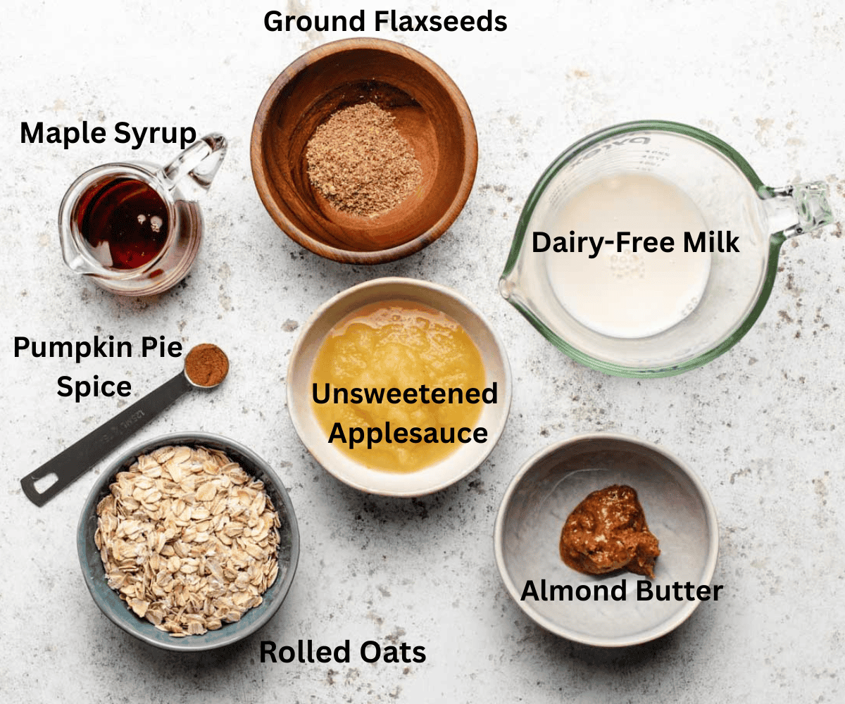 A bowl of ground flax seeds, dairy-free milk, maple syrup, unsweetened applesauce, pumpkin pie spice, rolled oats, and almond butter.