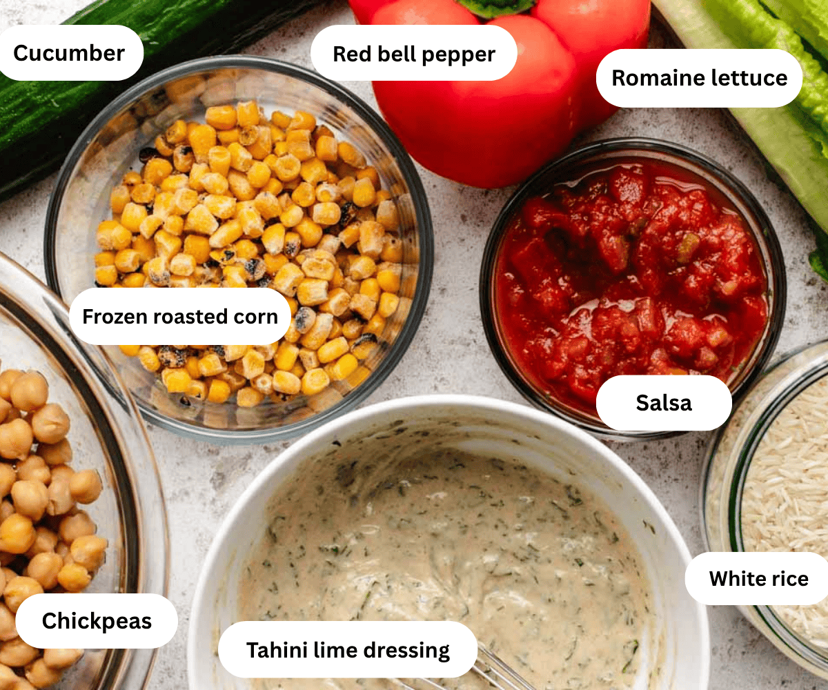 A cucumber, a red bell pepper, romaine lettuce, a bowl of corn, salsa, chickpeas, tahini dressing, and white rice.