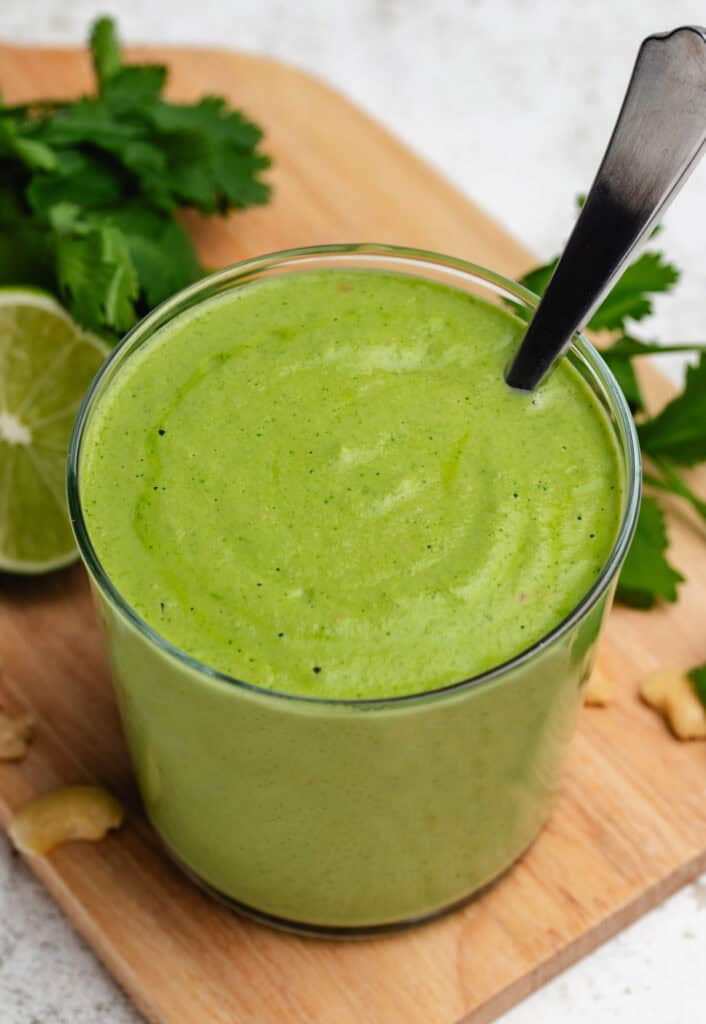 Vegan cilantro sauce in a glass jar with a spoon.