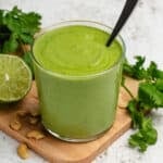 Cilantro cashew dressing in a glass with a spoon.