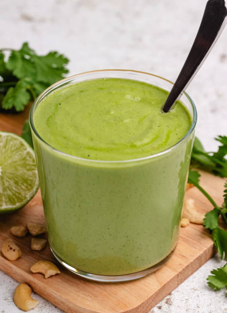 Vegan cilantro crema in a glass with a spoon.