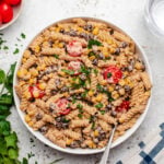 Vegan taco pasta salad with cherry tomatoes in a white bowl with a fork.