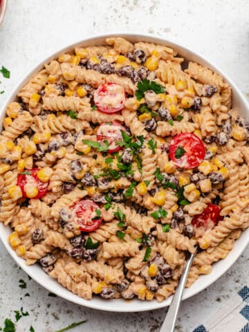 Vegan taco pasta salad with cherry tomatoes in a white bowl with a fork.