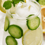 Lemon Cucumber and mint water in a glass with a lemon slice and a mint sprig.