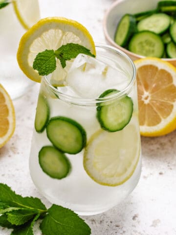 Lemon mint cucumber water in a glass with a lemon slice and a mint sprig.