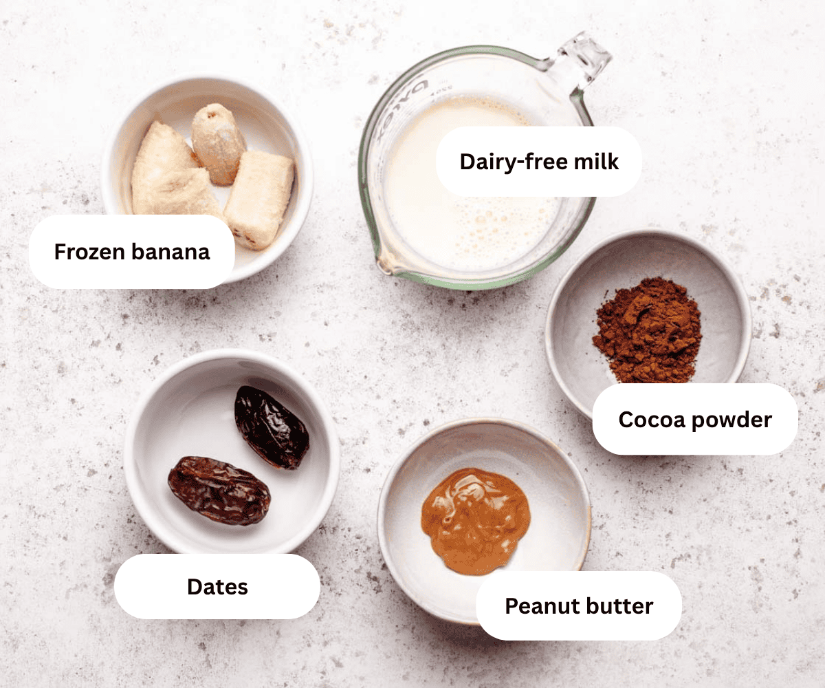A bowl of frozen banana, dairy-free milk, cocoa powder, peanut butter, and dates.