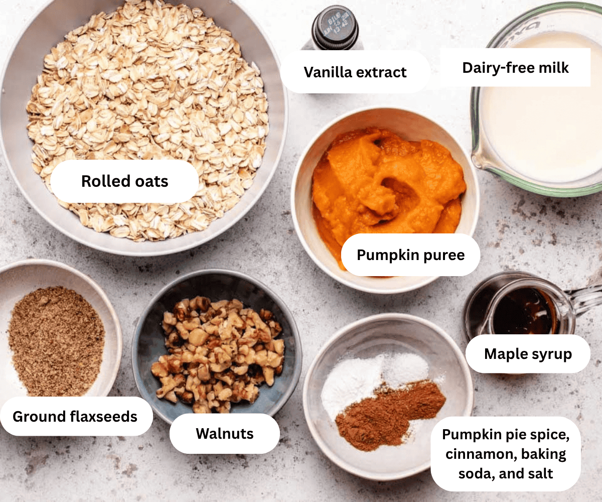A bowl of rolled oats, pumpkin puree, dairy-free milk, vanilla extract, ground flaxseeds, walnuts, spices, and maple syrup.