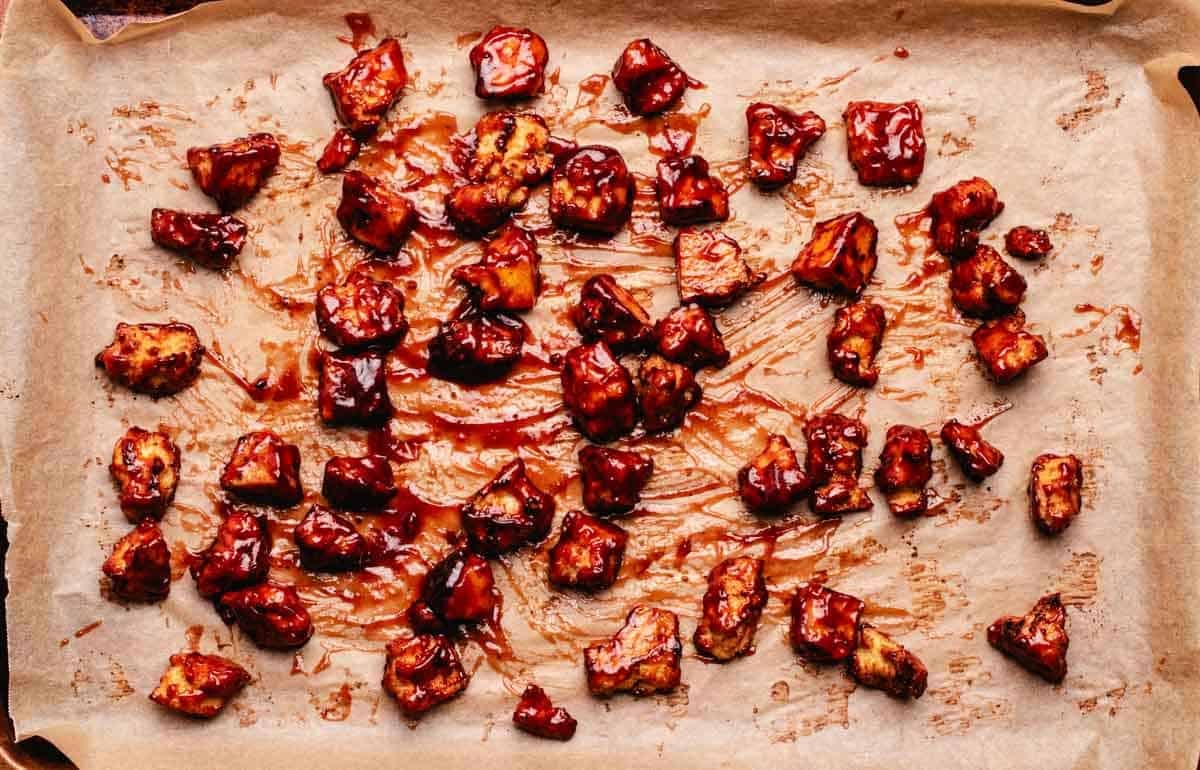 Baked tofu with barbecue sauce on a baking tray with parchment paper.