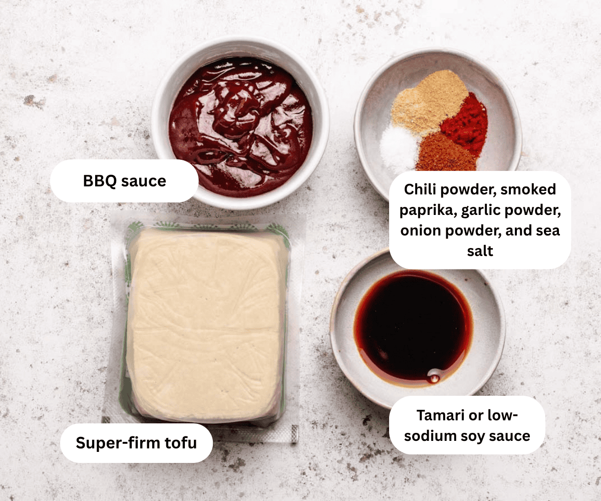 BBQ sauce in a bowl, a bowl of spices, a bowl of soy sauce, and a block of tofu.