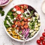 BBQ tofu salad with corn, cherry tomatoes, lettuce, red onions, cucumbers, black beans, and vegan ranch dressing in a bowl with a fork.