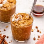 Vegan pumpkin overnight oats in a glass jar with dairy-free yogurt and walnuts on top.