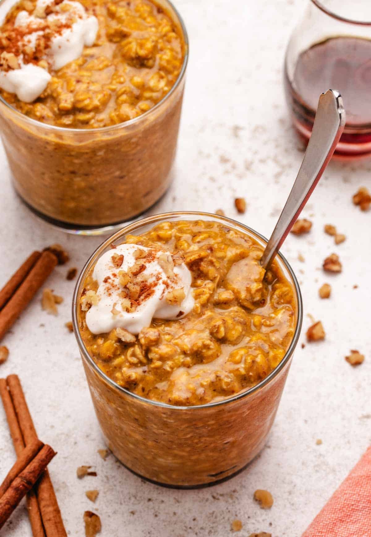 Pumpkin spice overnight oats in a glass jar with dairy-free yogurt and walnuts on top.